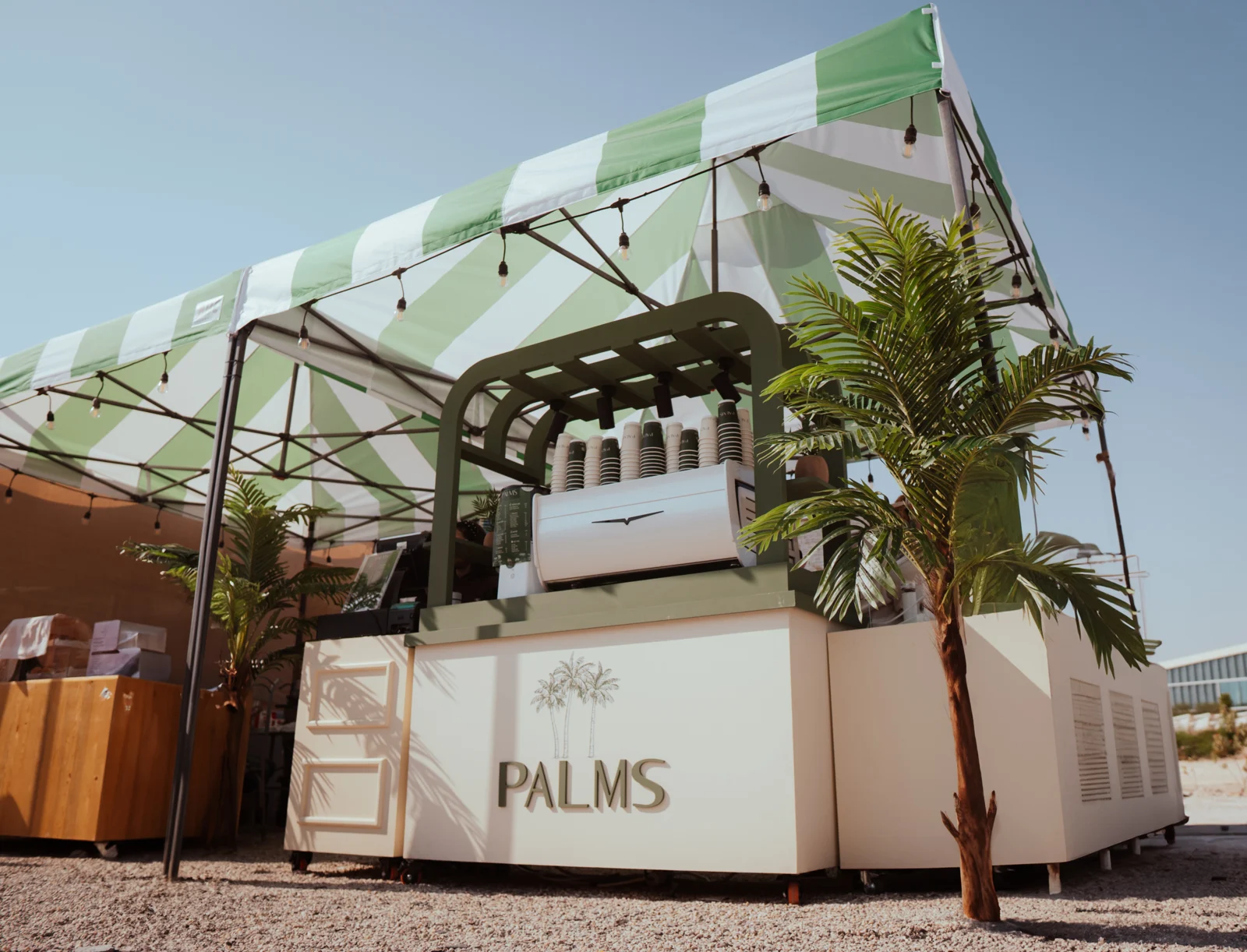 PALMS kiosk under a green striped canopy