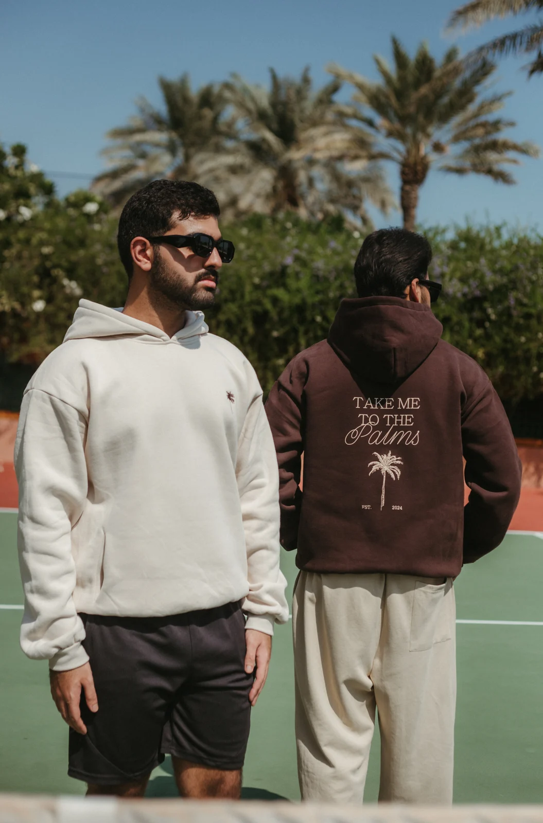 Two models in PALM’S hoodies on an outdoor tennis court