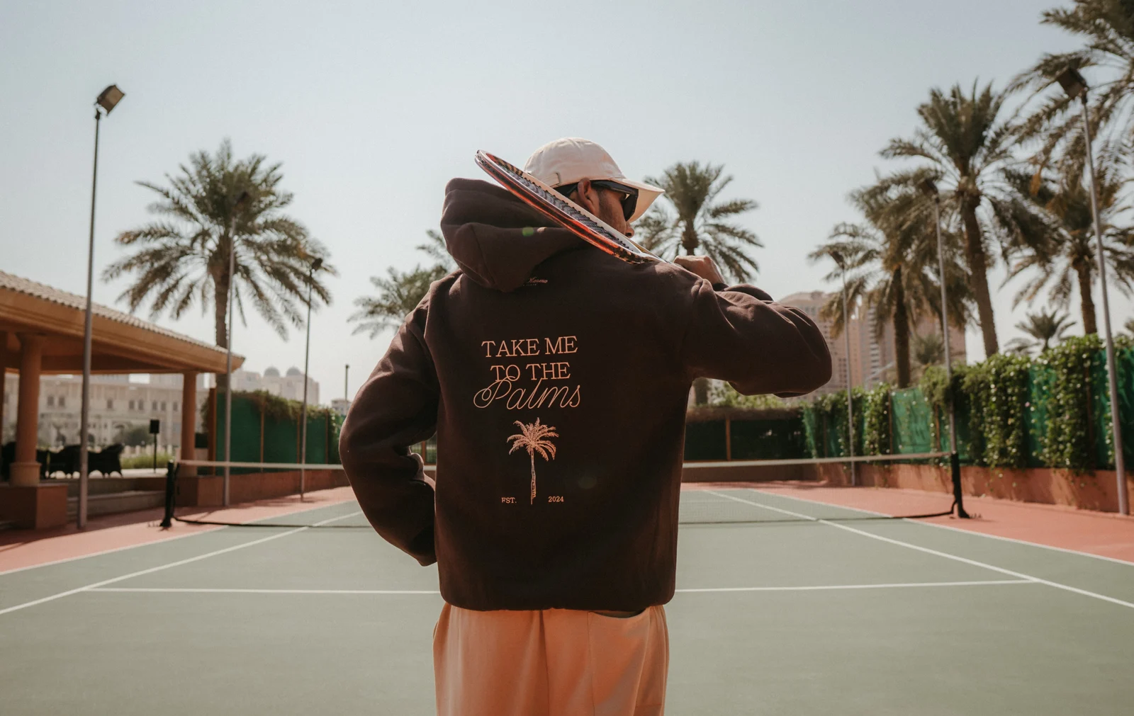 Models in PALM’S clothing beside palms on a tennis court