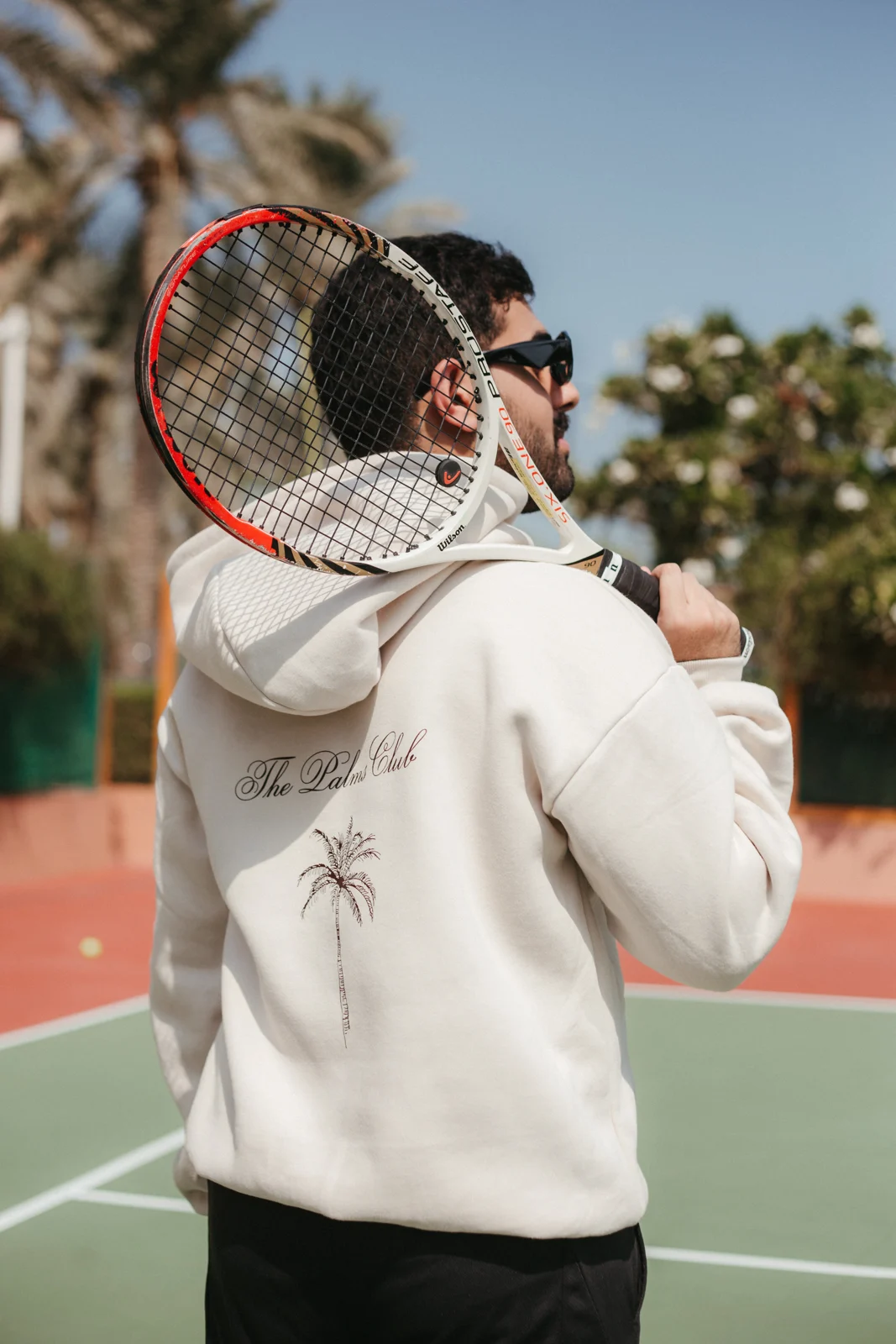Model holding a tennis racket in a white hoodie